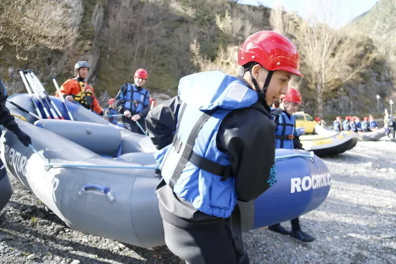 En primer pla de la imatge un noi carregant una barca, al fons altres nois carregant la barca per entrar al riu. Imatge del 5 de abril de 2017. (horitzontal)