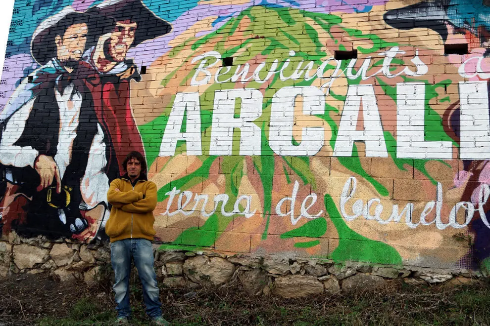 Xavi Pedemonte davant del mural que dona la benvinguda al poble d'Arcal&radic;&ne;s i est&radic;&dagger; dedicat als bandolers. imate del 26 de novembre del 2018. (horitzontal)