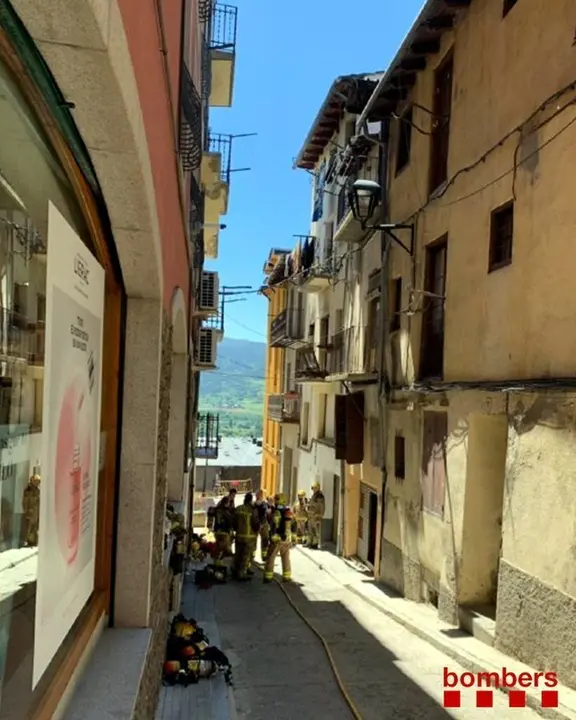 Pla general de l'edifici afectat pel foc a Puigcerd&agrave; i bombers treballant al carrer. El 16 de juny de 2019. (Vertical)