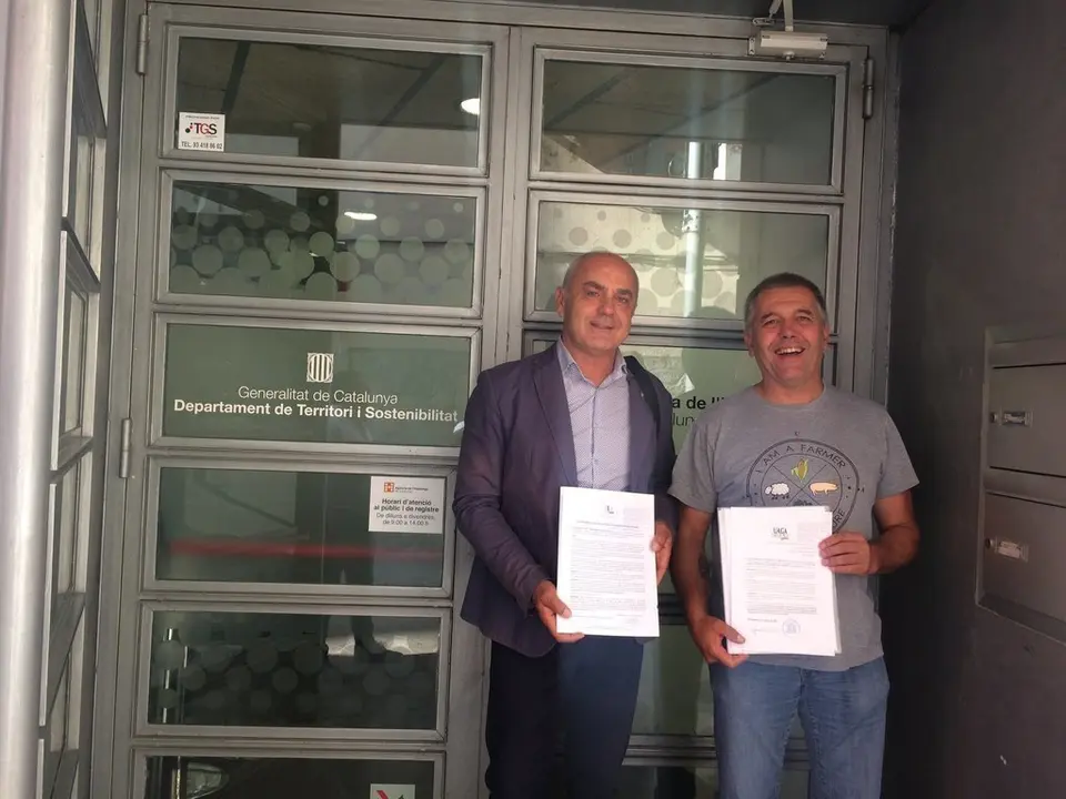 Representants de Joves Agricultors i Ramaders de Catalunya (JARC) i Uni&oacute;n de Agricultores y Ganaderos de Arag&oacute;n (UAGA-COAG) mostrant l'escrit que han presentat al departament de Territori de la Generalitat el 2 d'agost del 2019. (horitzontal)