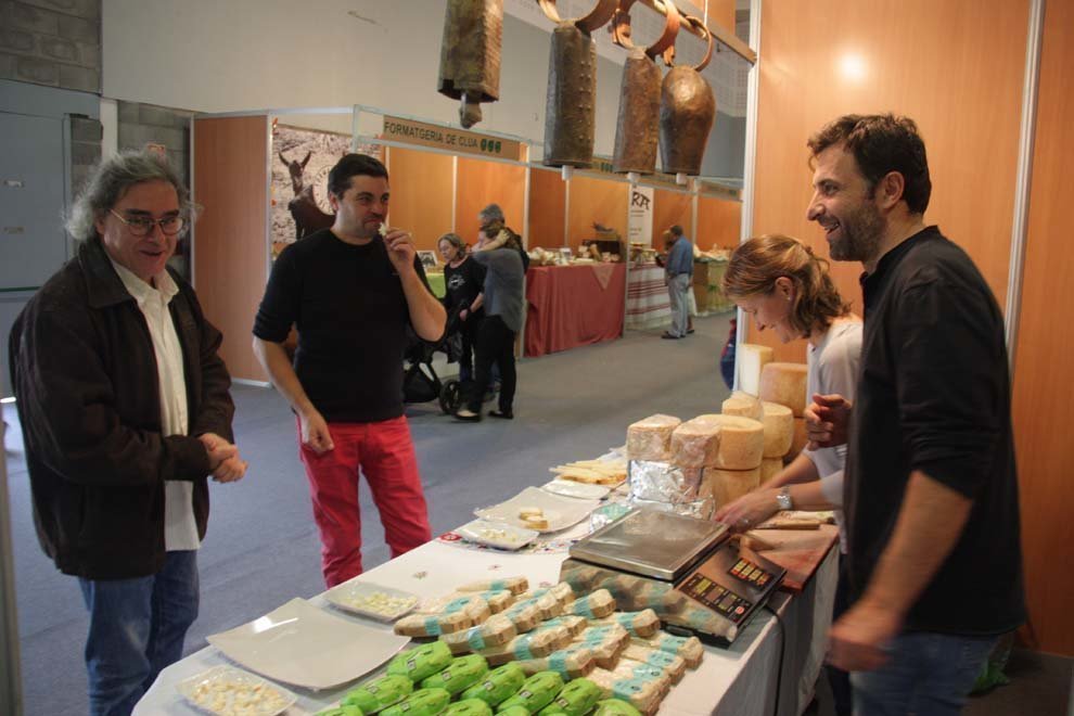 Pla general d'un dels expositors de formatge de la Fira de Formatges Artesans del Pirineu que acull la Seu d'Urgell, fent degustar el producte a alguns visitants, el 19 d'octubre de 2018 (Horitzontal).