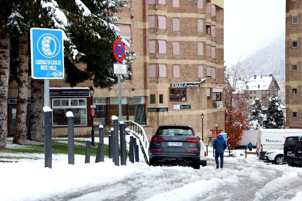 Un carrer de Baqueira ple ne neu amb un rètol que indica l'ús de cadenes en cas de neu i gel. Imatge del 6 de novembre del 2019. (horitzontal)