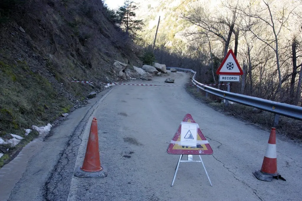Pla general d'un senyal de carretera tallada al punt on han caigut diverses roques a la cal&ccedil;ada, a la carretera local que va des de l'N-145 a diversos nuclis del municipi de les Valls de Valira (Alt Urgell). Imatge del 5 de febrer de 2020 (Horitzontal).