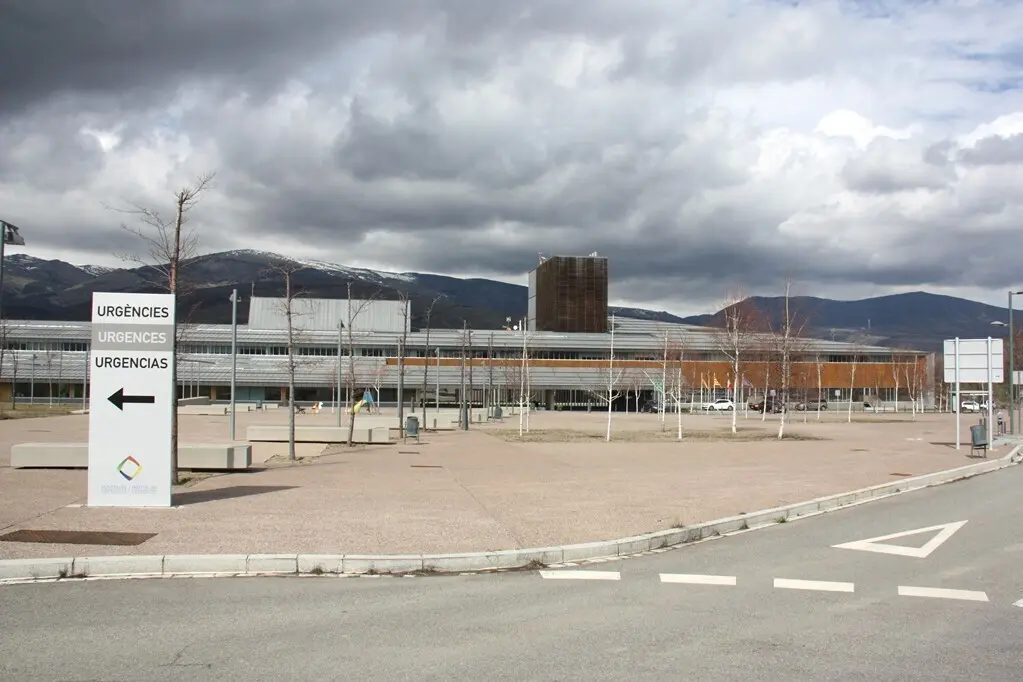 Pla general de l'exterior de l'edifici de l'Hospital de Cerdanya, on es veu en primer terme un cartell que indica on est&agrave; la zona d'Urg&egrave;ncies. Imatge del 13 de mar&ccedil; de 2020 (Horitzontal).