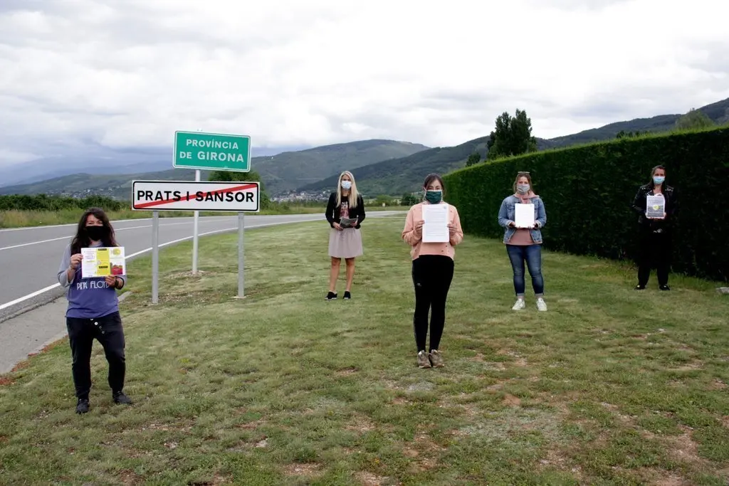 Pla general de diverses integrants de la Plataforma Docents Substituts de Cerdanya mostrant el manifest i material de difusi&oacute; al l&iacute;mit provincial entre Lleida i Girona situat al terme de Prats i Sansor. Imatge del 10 de juny de 2020 (Horitzontal).