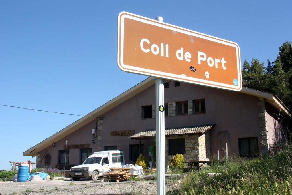 Pla obert on es veu en primer terme un cartell de la carretera que indica l'arribada al Coll de Port i, al fons, el refugi que porta el mateix nom i que l'Ajuntament de Josa i Tuixén està en procés d'arrendament, el 23 de juny de 2020 (Horitzontal).