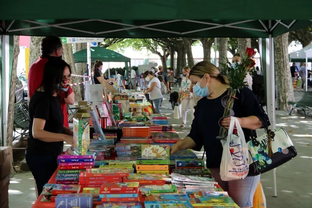 Una dona amb un ram de roses a una parada de llibres de la Seu d'Urgell el 23 de juliol del 2020. (horitzontal)