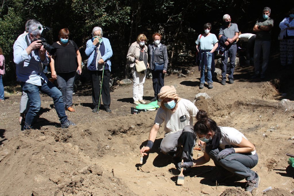 Pla obert de dos arqueòlegs analitzant el què han trobat en l'excavació d'una fossa de la Guerra Civil a Sorpe, a l'Alt Àneu (Pallars Sobirà), i familiars de les víctimes que hi hauria enterrades mirant-ho darrere, el 2 de setembre de 2020 (Horitzontal).