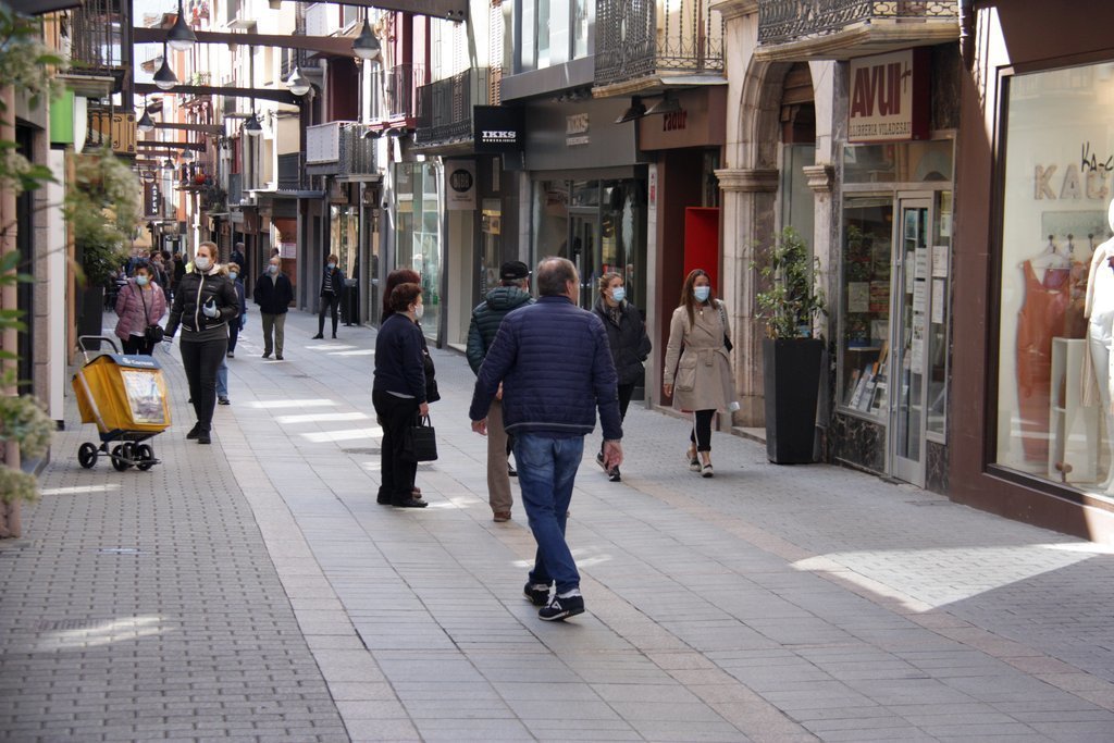 Pla obert del carrer Major de Puigcerdà on es veuen botigues obertes i gent passejant amb mascareta. Imatge del 12 de maig de 2020 (Horitzontal).