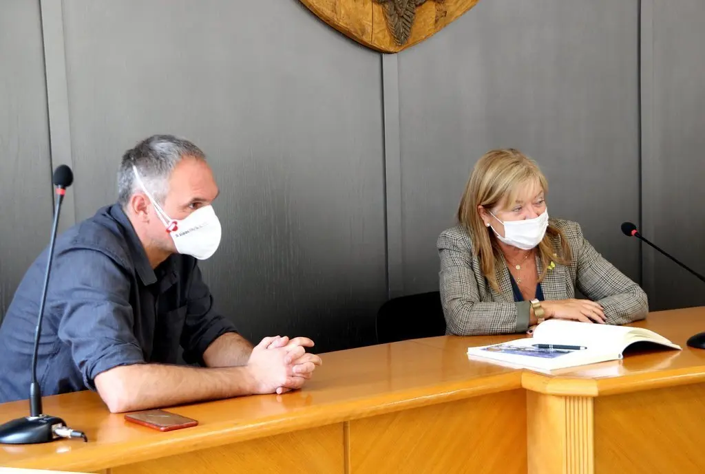 Pla mig de la consellera de Cultura, &Agrave;ngels Ponsa, a l'Ajuntament de Sort signant el llibre d'honor, acompanyada de l'alcalde de la localitat, Raimon Monterde. Imatge del 24 de setembre del 2020. (Horitzontal)