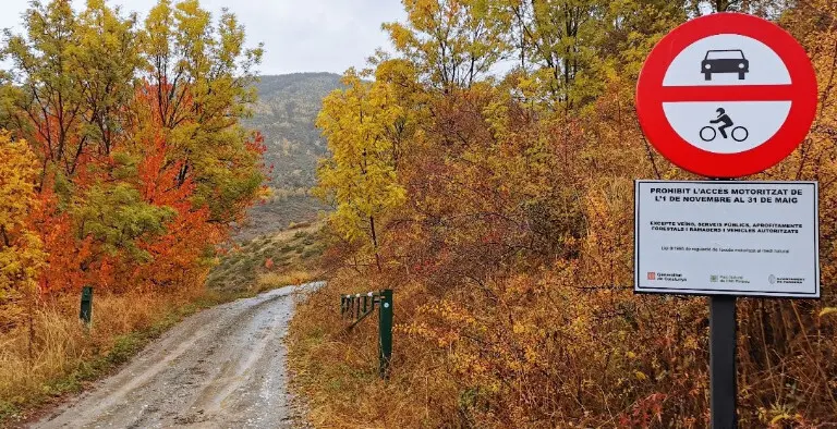 Pla general d'una pista d'acc&eacute;s a Santa Magdalena i un r&egrave;tol indicador de la regulaci&oacute; d'acc&eacute;s motoritzat. (horitzontal)