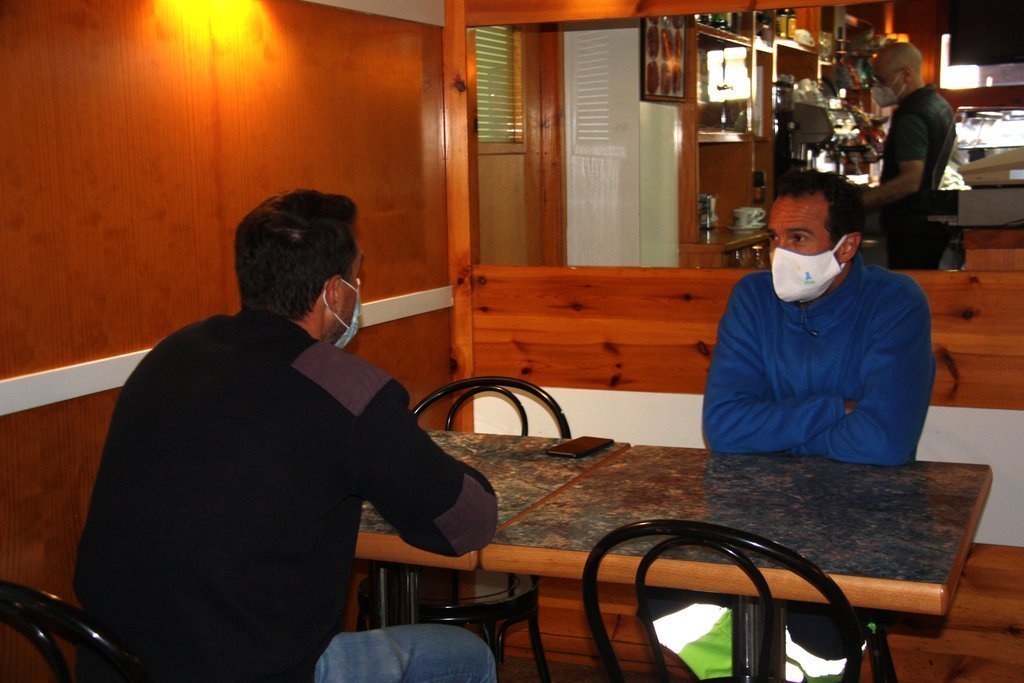 Pla mitjà de dos clients asseguts en una taula d'un bar del nucli d'Adrall, a Ribera d'Urgellet (Alt Urgell), en el primer dia de reobertura del sector de la restauració. Imatge del 23 de novembre de 2020 (Horitzontal).