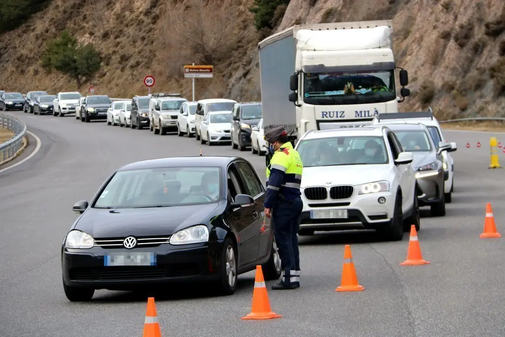 Pla obert on es veu un mosso parant un dels vehicles que accedien al t&uacute;nel del Cad&iacute; (C-16) en direcci&oacute; sud i la cua de cotxes al darrere en el segon dia de confinament perimetral de la Cerdanya. Imatge del 24 de desembre de 2020 (Horitzontal).