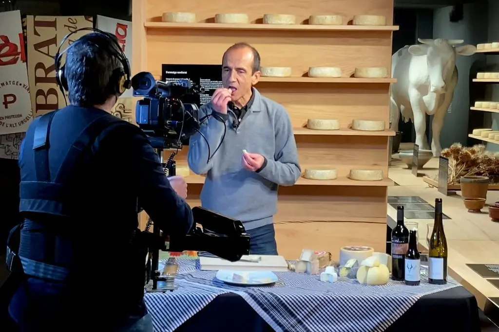 Pla obert del gastr&ograve;nom Pep Palau tastant un formatge durant la gravaci&oacute; d'un nou v&iacute;deo per al canal virtual de la Fira de Sant Ermengol de la Seu d'Urgell i on es veu tamb&eacute; el c&agrave;mera encarregat de l'audiovisual, el 28 de gener de 2021 (Horitzontal).