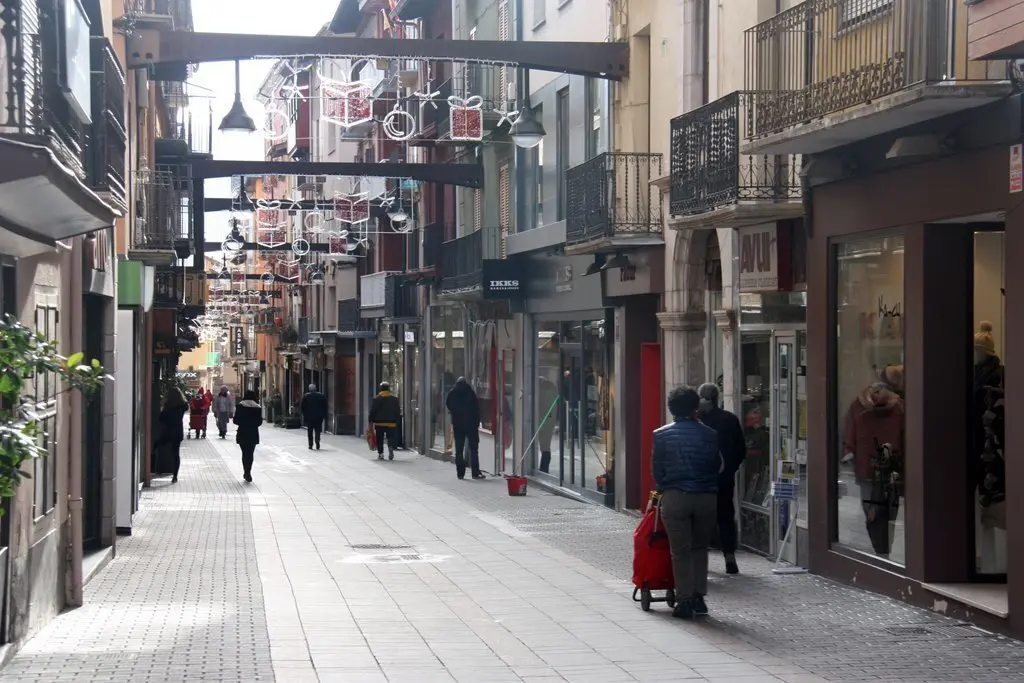 Pla obert on es veuen algunes persones passejant pel carrer Major de Puigcerd&agrave;, amb menys aflu&egrave;ncia de gent pel confinament perimetral de la Cerdanya. Imatge del 29 de desembre de 2020 (Horitzontal).