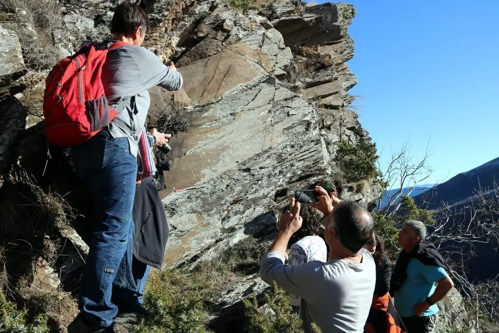 Imatge de ve&iuml;ns observant les roques on estan esculpits els gravats a la vall d'&Agrave;ssua. Imatge del 3 de gener del 2019. (horitzontal)