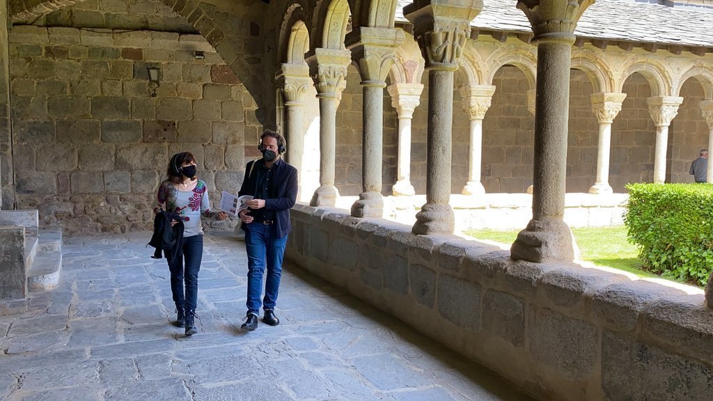 Pla obert de la delegada de Patrimoni Cultural del Bisbat d'Urgell, Clara Arbués, i el tècnic en cultura i patrimoni Jordi Quer, al claustre de la catedral de la Seu d'Urgell seguint un nou itinerari de visita. Imatge del 18 de maig de 2021. (Horitzontal)