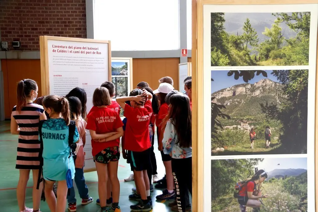 Pla de detall d'un grup d'escolars visitant la mostra 'Hist&ograve;ries i Camins. Passeig literari pels camins pirinencs' el 21 de maig del 2021. (Horitzontal)