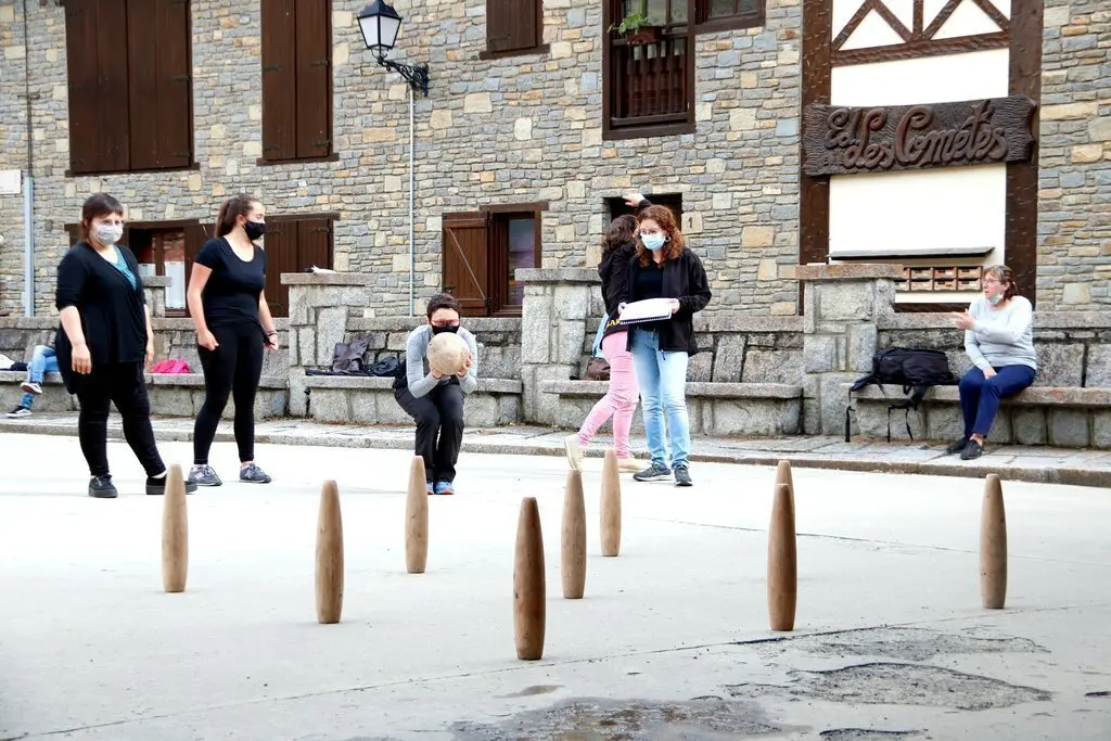Primer pla de les bitlles pallareses i al fons una jugadora preparada per fer una tirada. Imatge del 30 de maig del 2021. (horitzontal)
