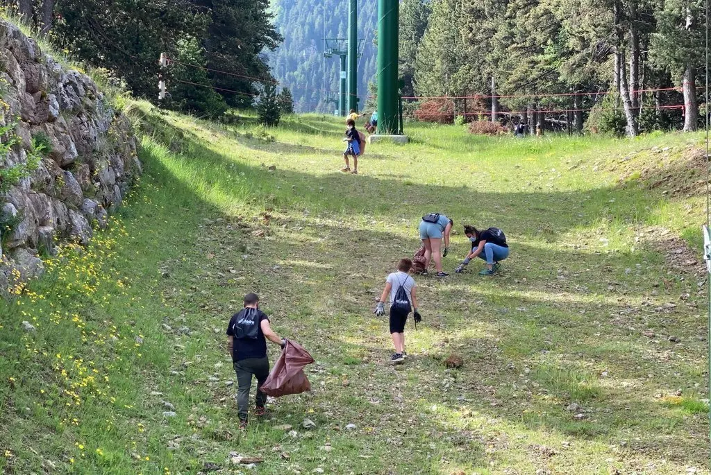 Pla obert d'un grup d'alumnes de l'Escola Bac de Cerdanya d'Alp recollint residus sota un remuntador de l'estaci&oacute; de La Molina. Imatge del 16 de juny de 2021. (Horitzontal)