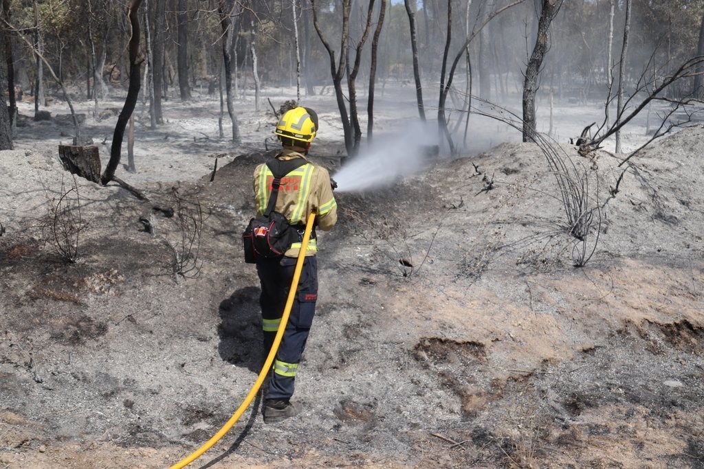 Pla mitjà d'un bomber remullant una de les zones cremades a l'incendi de Ventalló aquest diumenge 25 de juliol de 2021. (Horitzontal)