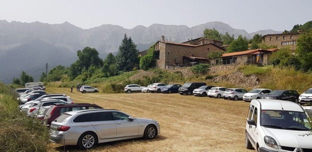 Imatge del camp habilitat aquest estiu com a aparcament provisional a l'entrada de l'EMD d'Estana, al municipi de Montellà i Martinet, el 26 d'agost del 2021. (Horitzontal)