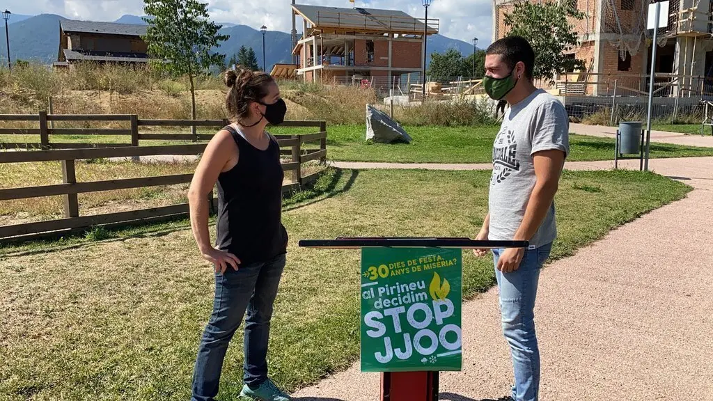 Pla sencer de dos portaveus de la Plataforma Stop JJOO, Helena Guill&eacute;n i Bernat Lavaquiol, presentant l'entitat davant d'un bloc d'habitatges en construcci&oacute; a Bellver de Cerdanya. Imatge del 30 d'agost de 2021. (Horitzontal)