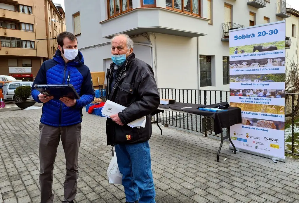 Pla general d'un t&egrave;cnic del programa Sobir&agrave; 20-30 fent una enquesta al carrer el dia del mercat de Sort el 13 de gener del 2021. (horitzontal)