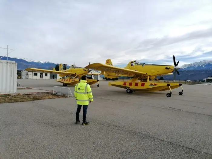 Pla obert on es veu un operari, d'esquena, amb els dos avions de vigil&agrave;ncia i atac que els Bombers tenen a la base de l'aeroport d'Andorra-La Seu. Imatge publicada el 3 de desembre de 2021. (Horitzontal)