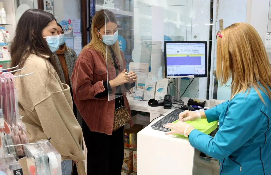Pla mitj&agrave; de diverses noies esperant el torn per fer-se un test d'ant&iacute;gens en una farm&agrave;cia, el 28-12-21 (Horitzontal).