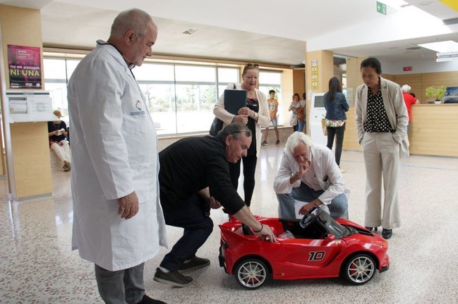 Pla general on es veu al director de l'Hospital de Cerdanya, Francesc Bonet, a l'esquerra, i el cap de pedriatria, Eduard Carreras, dreta, mirant amb membres de Proj'aide 66 el cotxet que els ha donat l'entitat, el 27 de setembre de 2019 (Horitzontal).