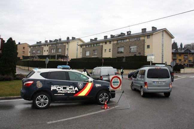 Pla general on es veu un vehicle de la policia espanyola i diversos cotxes aturats a la rotonda d'accés a Puigcerdà des de la Guingueta d'Ix, a l'Alta Cerdanya, o la carretera de l'enclavament de Llívia. Imatge del 17 de març de 2020 (Horitzontal).