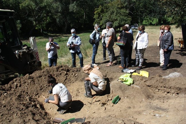 Pla obert de dos arqueòlegs treballant en l'excavació d'una fossa de la Guerra Civil a Sorpe, a l'Alt Àneu (Pallars Sobirà), i familiars de les víctimes que hi hauria enterrades mirant-ho al seu costat, el 2 de setembre de 2020 (Horitzontal).
