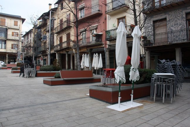 Pla obert on es veuen taules i cadires recollides de diversos bars de la plaça Cabrinetty de Puigcerdà el primer dia de confinament perimetral de la Cerdanya. Imatge del 23 de desembre de 2020 (Horitzontal).