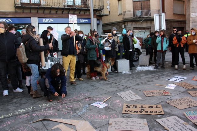 Pla obert on es veuen diversos manifestants protestant a la plaça de l'Ajuntament de Puigcerdà pel confinament perimetral de la Cerdanya, on es veuen les pancartes al terra i una persona escrivint amb guix. Imatge del 31 de desembre de 2020 (Horitzontal).
