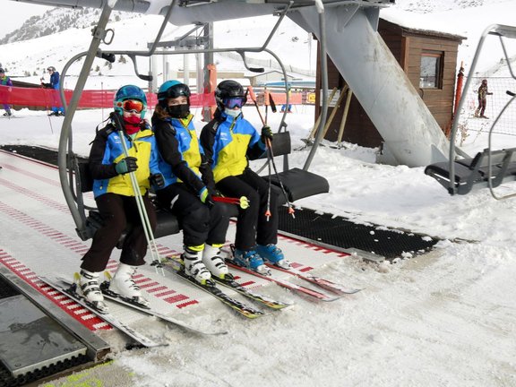 Pla general d'un grup de tres esquiadores pujant a un telecadira a l'estaci√≥ de Bo√≠ Ta√ºll el primer dia de la temporada 2021-2022, el 27 de novembre de 2021. (Horitzontal)