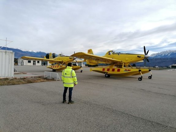 Pla obert on es veu un operari, d'esquena, amb els dos avions de vigilància i atac que els Bombers tenen a la base de l'aeroport d'Andorra-La Seu. Imatge publicada el 3 de desembre de 2021. (Horitzontal)