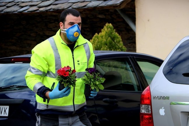 Un operari de l'Ajuntament de Sort amb dos flors a les mans per anar a deixar-les a la porta d'una casa el 15 d'abril del 2020. (horitzontal)