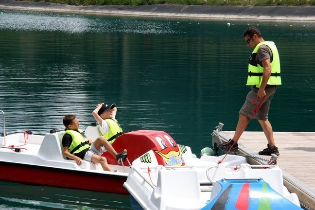 Pla de detall on es veuen dos nens i un monitor a punt de pujar a una barca del llac de la Molina (Cerdanya), el 3 de juliol de 2019 (Horitzontal).