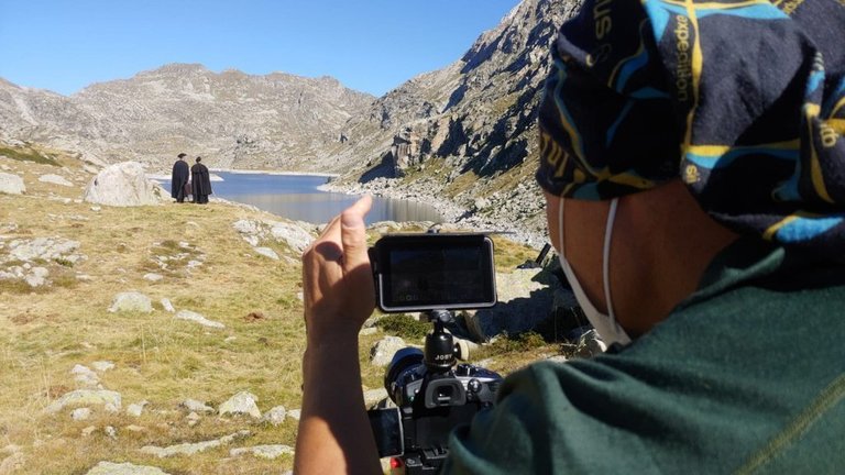 Pla obert on es veu part d'una càmera enregistrant a dos persones que estan al costat d'un estany de la Vall Fosca (Pallars Jussà). Imatge del 4 de setembre de 2020 (Horitzontal).