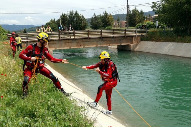 Pla general de dos bombers fent pràctiques de rescat aquàtic al canal de Gavet. Un bombers estira amb una coda a un altre que simulava haver caigut. Imatge del 28 de maig del 2021. (Horitzontal)