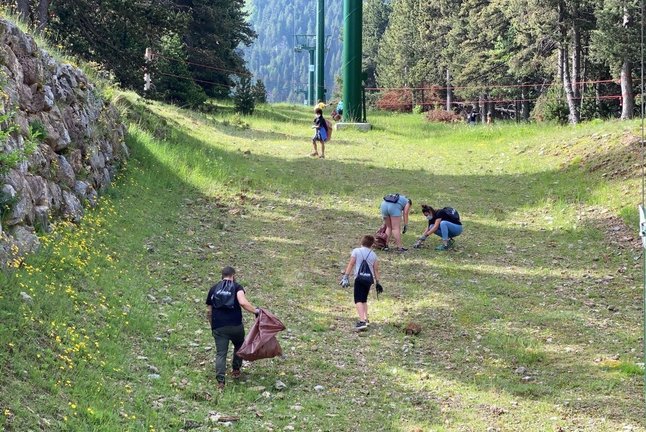 Pla obert d'un grup d'alumnes de l'Escola Bac de Cerdanya d'Alp recollint residus sota un remuntador de l'estació de La Molina. Imatge del 16 de juny de 2021. (Horitzontal)