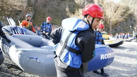 En primer pla de la imatge un noi carregant una barca, al fons altres nois carregant la barca per entrar al riu. Imatge del 5 de abril de 2017. (horitzontal)