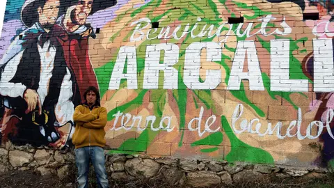 Xavi Pedemonte davant del mural que dona la benvinguda al poble d'Arcal&radic;&ne;s i est&radic;&dagger; dedicat als bandolers. imate del 26 de novembre del 2018. (horitzontal)
