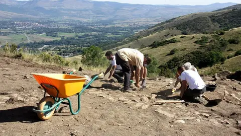 Pla general d'un grup d'arque&ograve;legs excavant el jaciment del Serrat del Castellar, a Fontanals de Cerdanya, on es veu part de la vall que hi queda a sota del tur&oacute;. Imatge del 29 d'agost de 2019 (Horitzontal).
