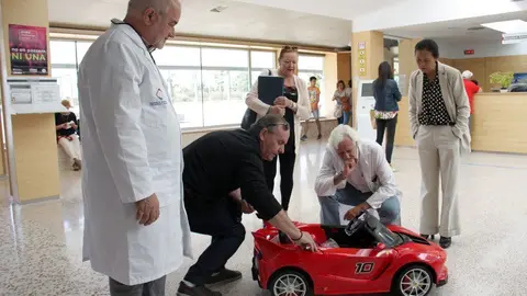 Pla general on es veu al director de l'Hospital de Cerdanya, Francesc Bonet, a l'esquerra, i el cap de pedriatria, Eduard Carreras, dreta, mirant amb membres de Proj'aide 66 el cotxet que els ha donat l'entitat, el 27 de setembre de 2019 (Horitzontal).
