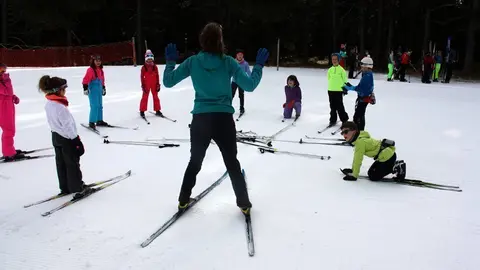 Pla general d'un grup d'alumnes del programa d'Esport Blanc Escolar amb una de les monitores a l'estaci&radic;&ge; d'esqu&radic;&ne; de fons d'Aransa, a Lles de Cerdanya. Imatge del 13 de gener de 2020 (Horitzontal).