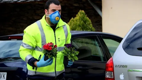 Un operari de l'Ajuntament de Sort amb dos flors a les mans per anar a deixar-les a la porta d'una casa el 15 d'abril del 2020. (horitzontal)