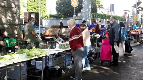 Pla general de diversos compradors equipats amb mascareta al costat d'una parada de fruites i verdures del mercat setmanal de la Seu d'Urgell. Imatge del 28 d'abril de 2020 (Horitzontal).