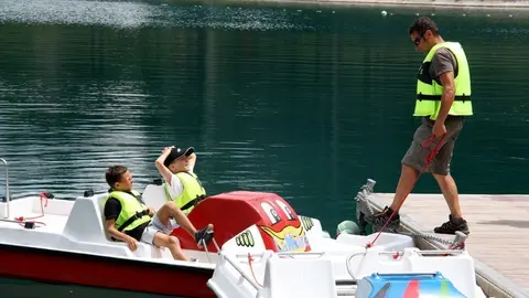 Pla de detall on es veuen dos nens i un monitor a punt de pujar a una barca del llac de la Molina (Cerdanya), el 3 de juliol de 2019 (Horitzontal).